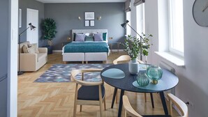 A modern bedroom with a bed, bedside tables, a window, and a dining area with chairs and a table. - Metro Politechnika Studio (Warsaw)