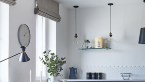 A modern kitchen with a dining area, featuring a round table, wooden chairs, a potted plant, and pendant lighting. - Metro Politechnika Studio (Warsaw)