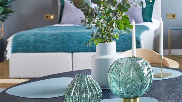 A modern bedroom with a bed, bedside tables, a bedside lamp, and a decorative plant on a table. - Metro Politechnika Studio (Warsaw)