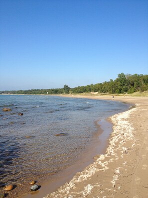 A beach with clear water, pebbles, and a sandy shore.