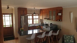 Une cuisine moderne avec des meubles en bois, un îlot central doté de tabourets, un réfrigérateur et un four encastré.