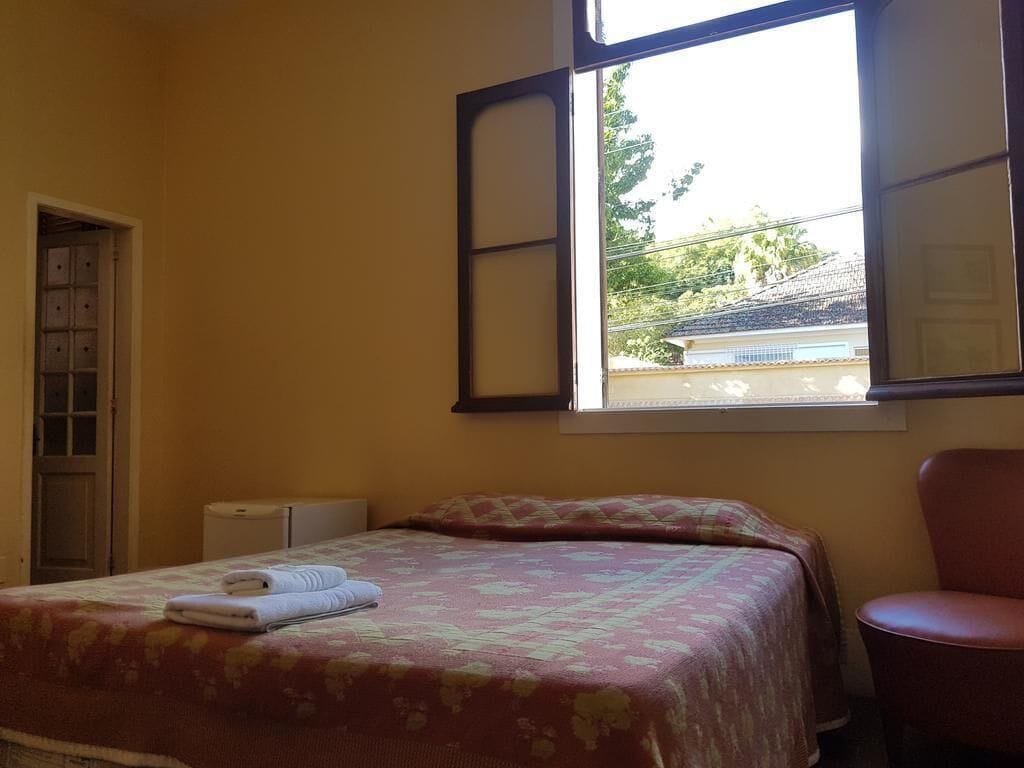 A bedroom with a bed, a chair, a window, and a door.
