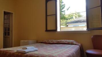 A bedroom with a bed, a chair, a window, and a door.