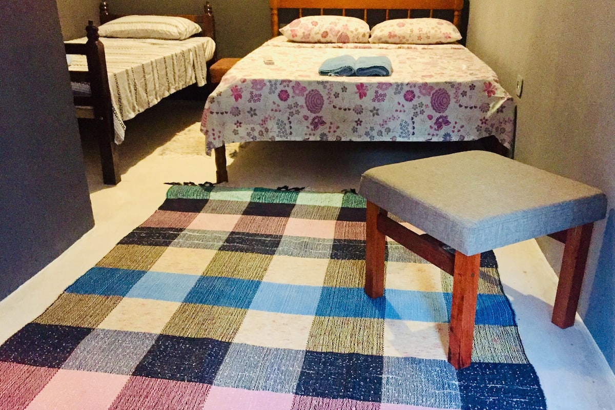 A bedroom with two single beds, a bench, and a checkered rug.
