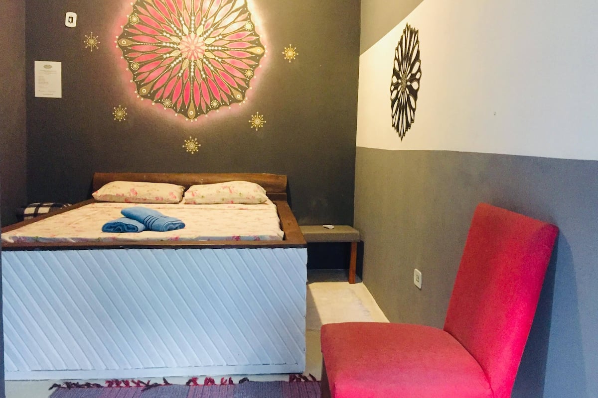 A bedroom with a bed, a red chair, and decorative wall art.