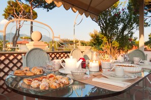 Une table dressée pour un repas, avec des pâtisseries, une théière, des tasses et une bougie.
