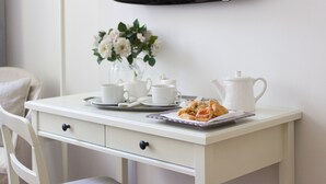 A white desk with a tray of pastries, a vase of flowers, and white cups and a teapot. - Forte Inn (Forte dei Marmi)