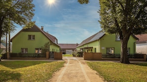 A pathway leading to a row of green houses with a clear sky and sunlight.