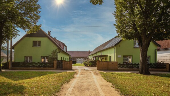 Un sendero que conduce a una hilera de casas verdes, con cielo despejado y luz solar.