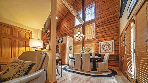 A wooden interior with a dining area, a leather chair, and a chandelier. - Cabins at Grand Mountain (Branson)