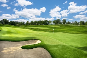 A golf course with well-manicured fairways, sand bunkers, and a flagstick indicating the hole.