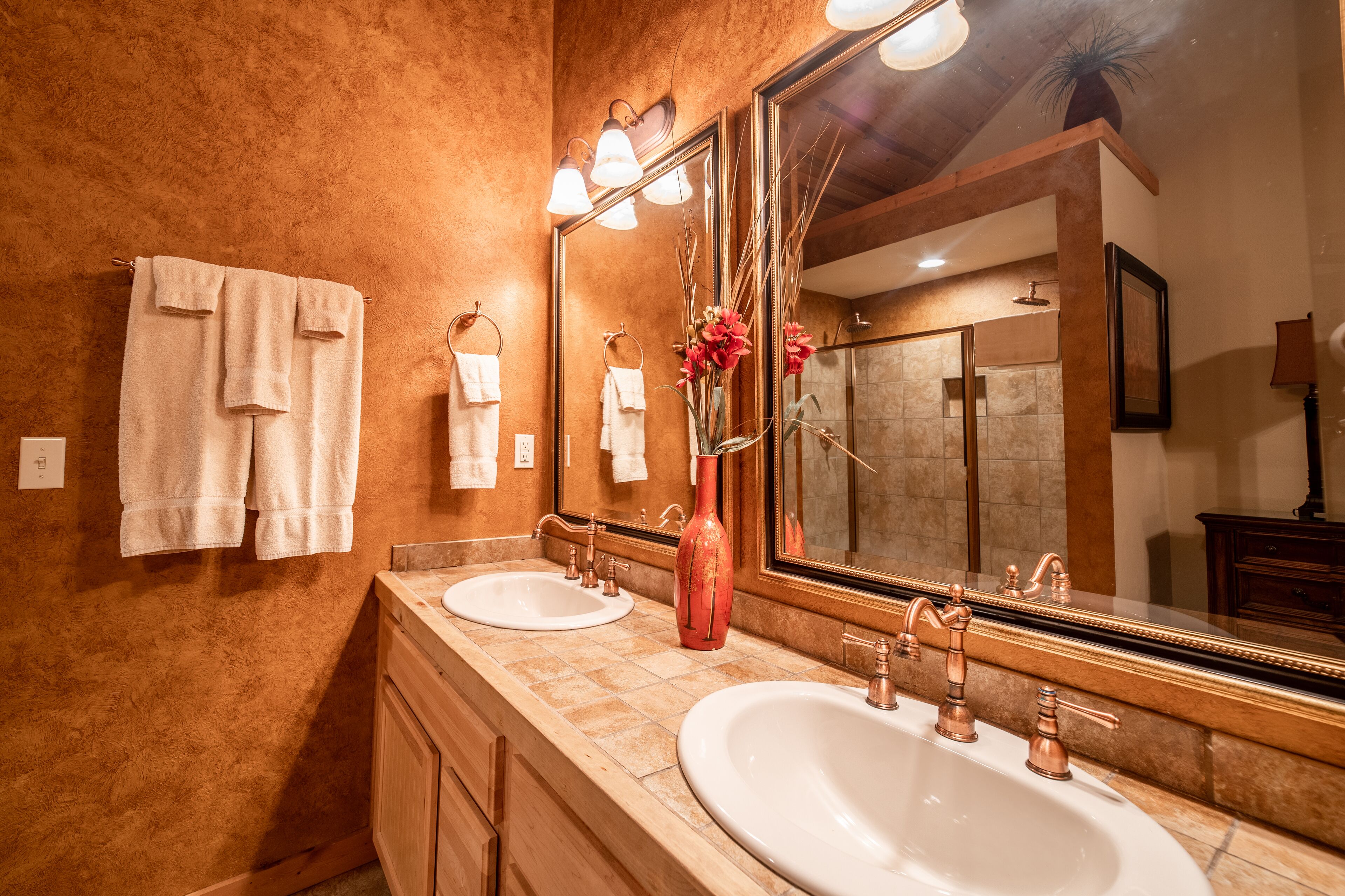 A bathroom with two sinks, a large mirror, and towels hanging on the wall.