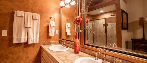 A bathroom with two sinks, a large mirror, and towels hanging on the wall.
