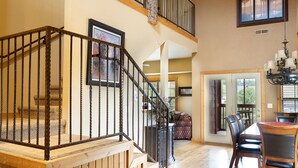 A spacious living area with a wooden staircase, a dining table with chairs, and a chandelier. - Cabins at Grand Mountain (Branson)