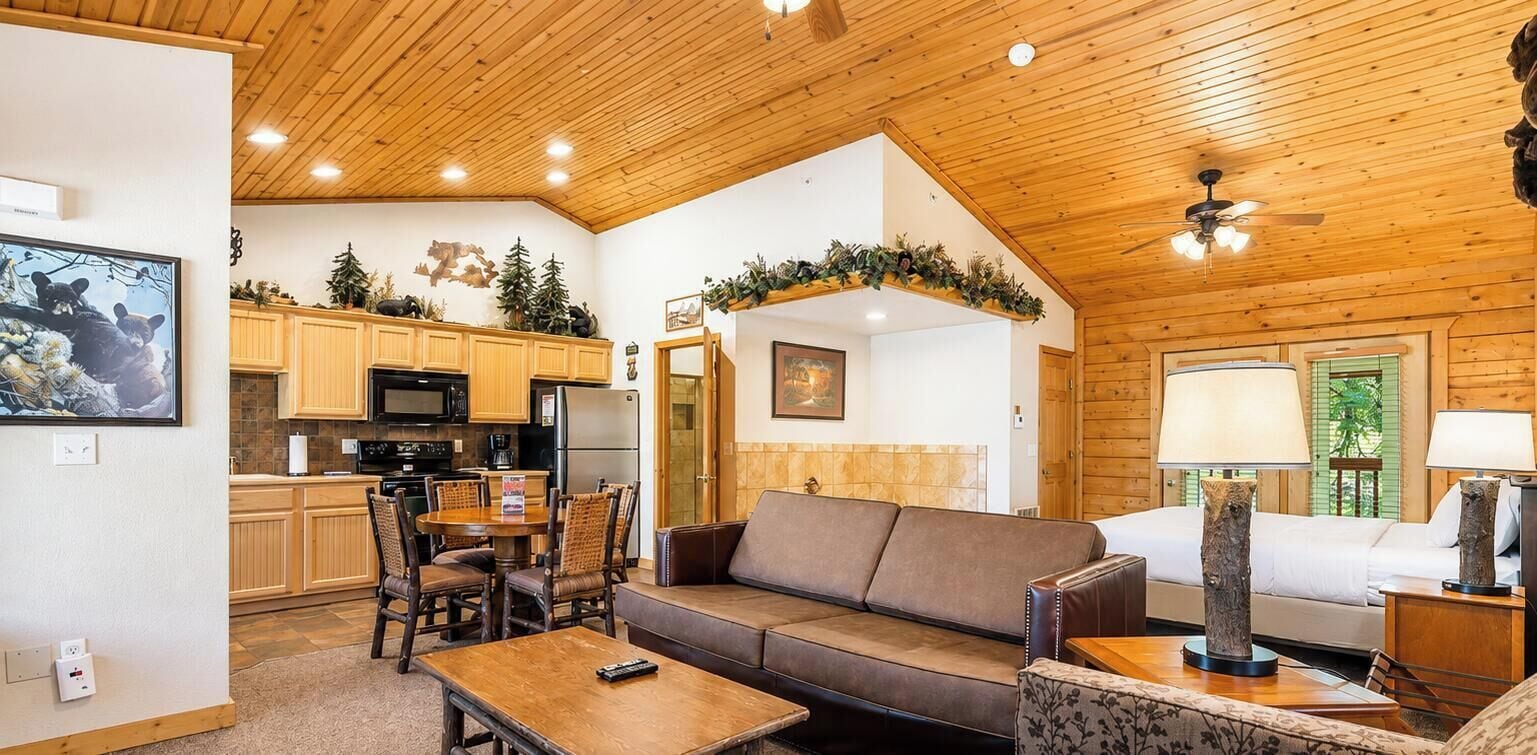Un ambiente accogliente con soffitto in legno, un'area pranzo con sedie, un divano e un letto con comodino.