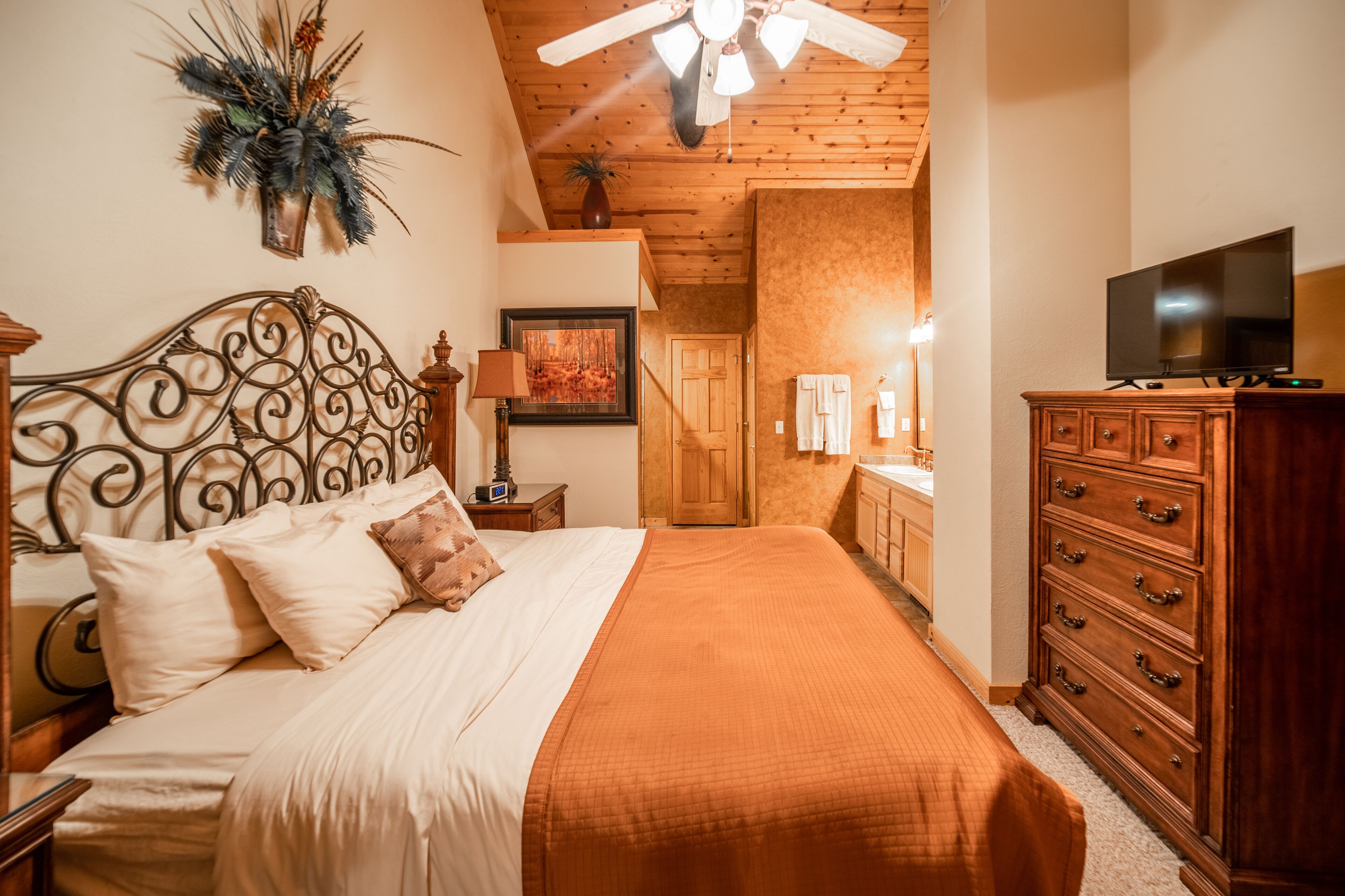 Un dormitorio con cama, cómoda de madera, televisor y ventilador de techo.