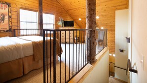 A bedroom with a bed, a television, a window, and a wooden ceiling. - Cabins at Grand Mountain (Branson)