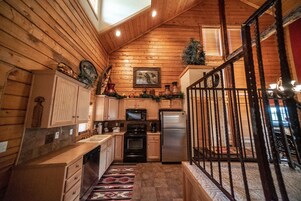 A log cabin-style kitchen with wooden walls, a stainless steel refrigerator, a microwave, and a stove.