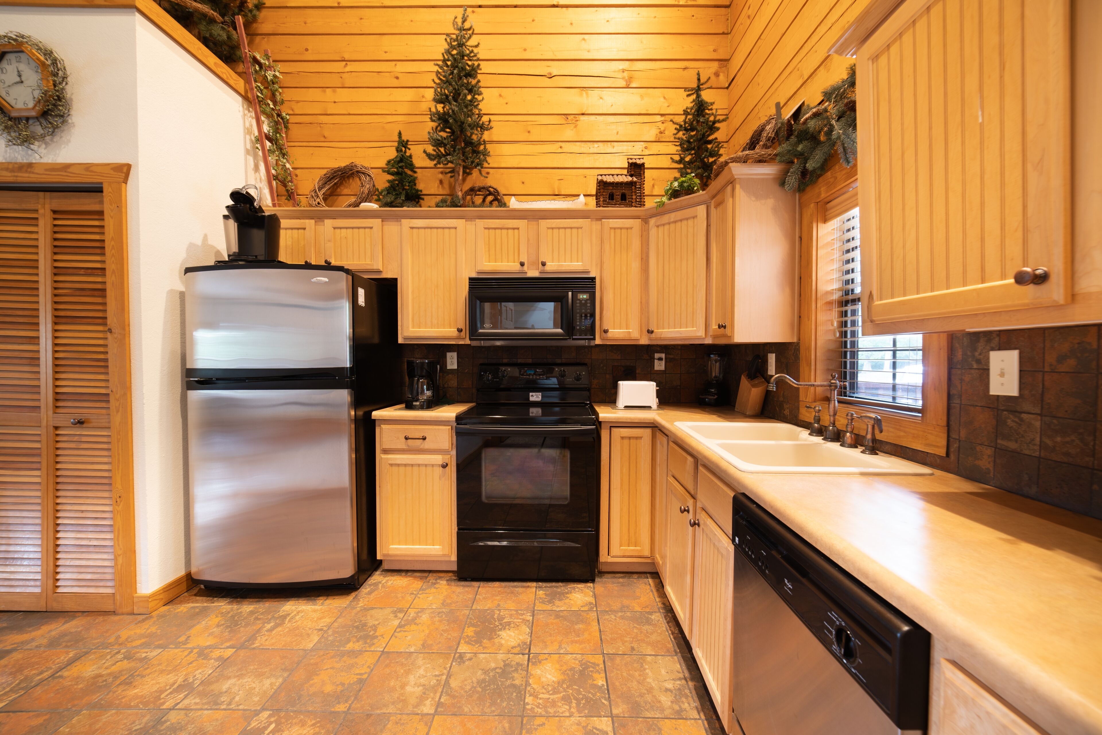 A kitchen with wooden cabinets, a stainless steel refrigerator, a microwave, an oven, and a dishwasher.