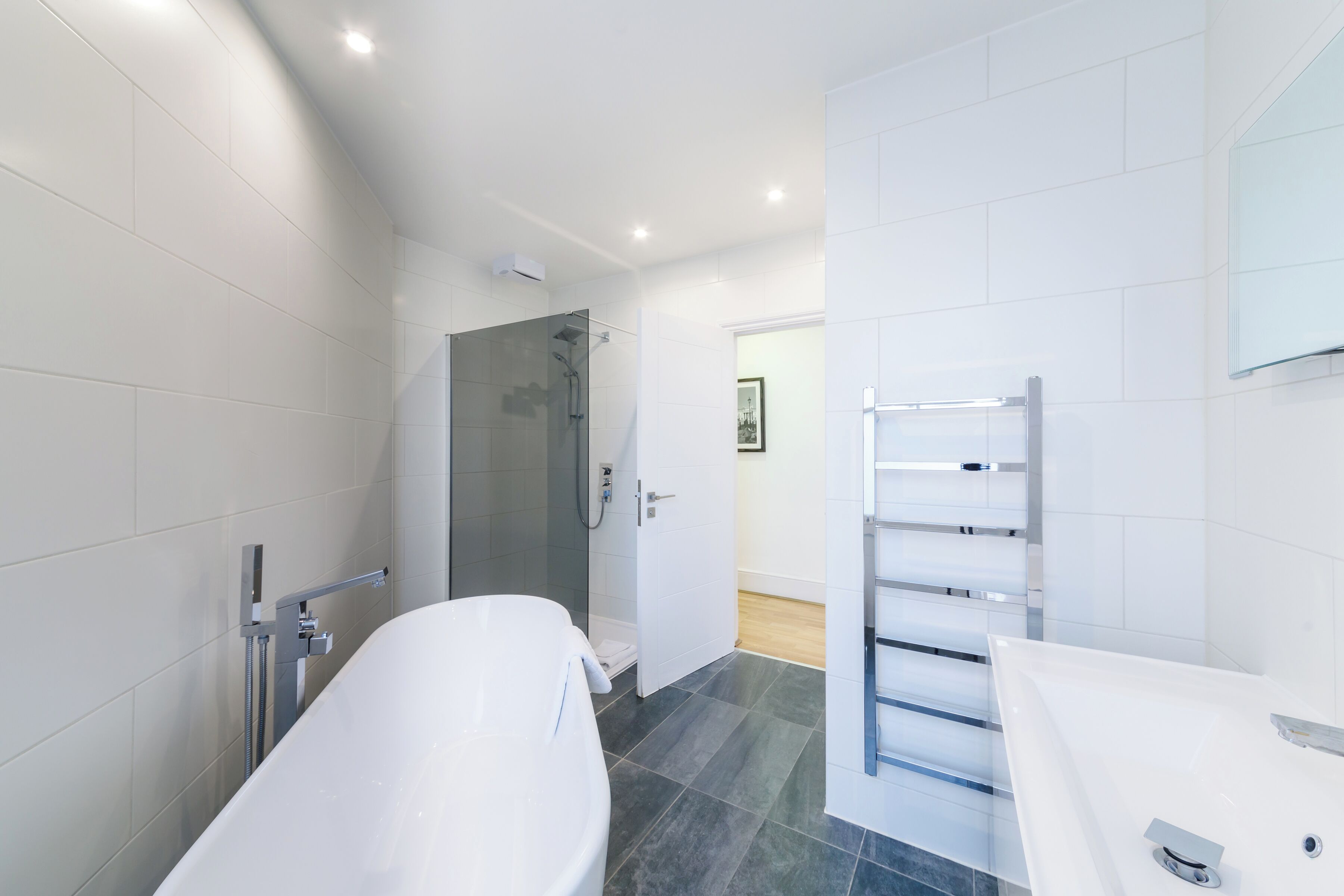 A modern bathroom with a freestanding bathtub, a glass-enclosed shower, and a white vanity with a mirror.