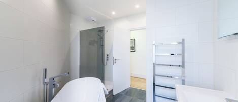 A modern bathroom with a freestanding bathtub, a glass-enclosed shower, and a white vanity with a mirror.