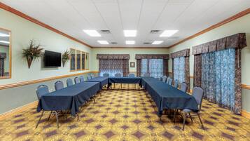 A conference room with a long table, chairs, and patterned carpet.