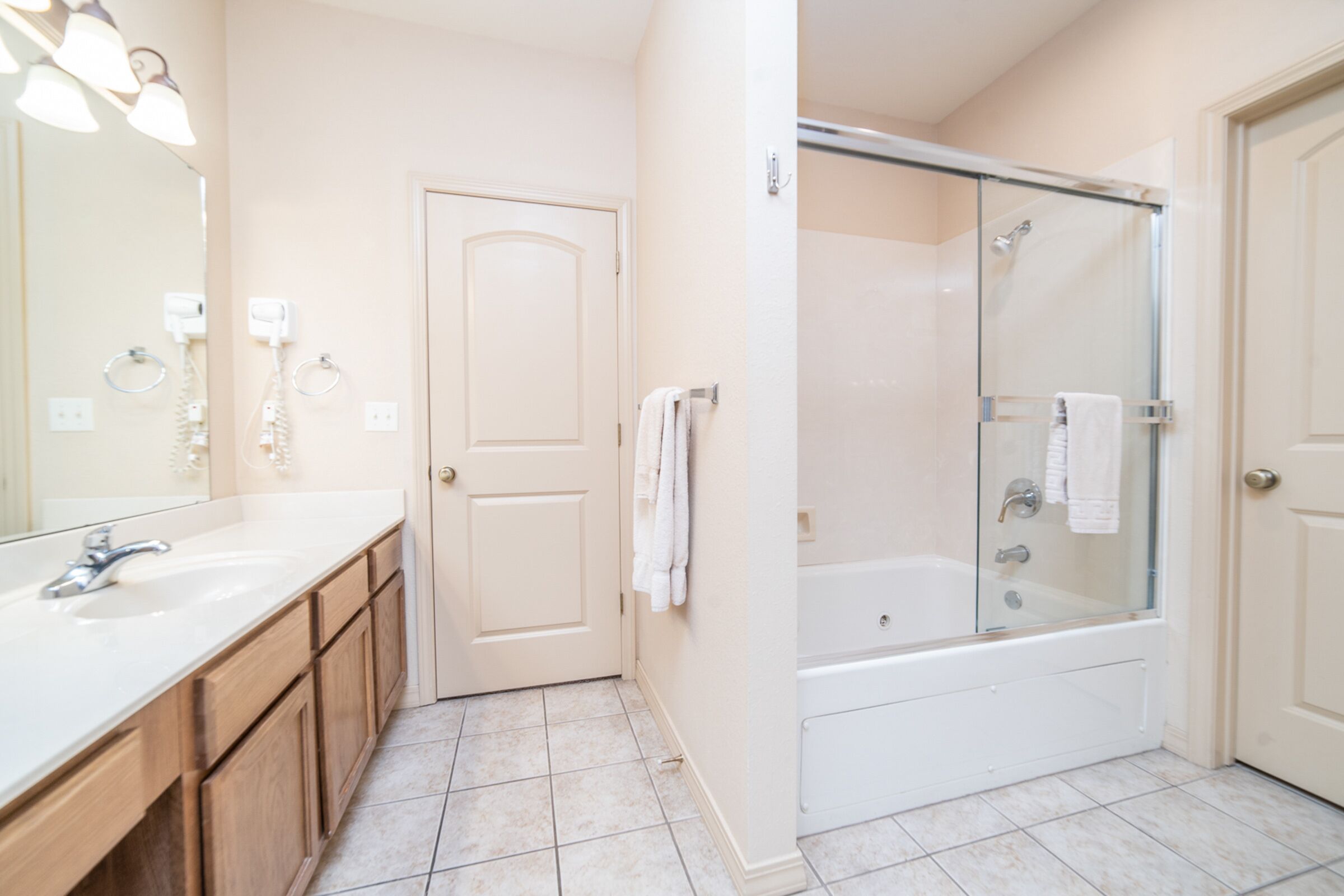 A modern bathroom with a large mirror, a sink, a shower, and a door.