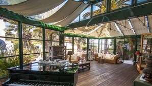 Une véranda avec un piano, un coin salon et des étagères à livres.