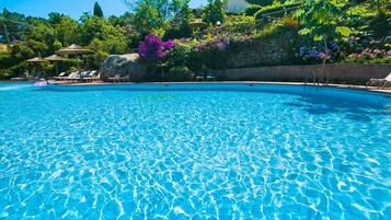 Una piscina al aire libre de temporada, sombrillas
