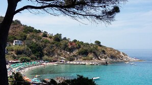 Une zone côtière avec une plage, des bateaux et des bâtiments situés sur une colline.