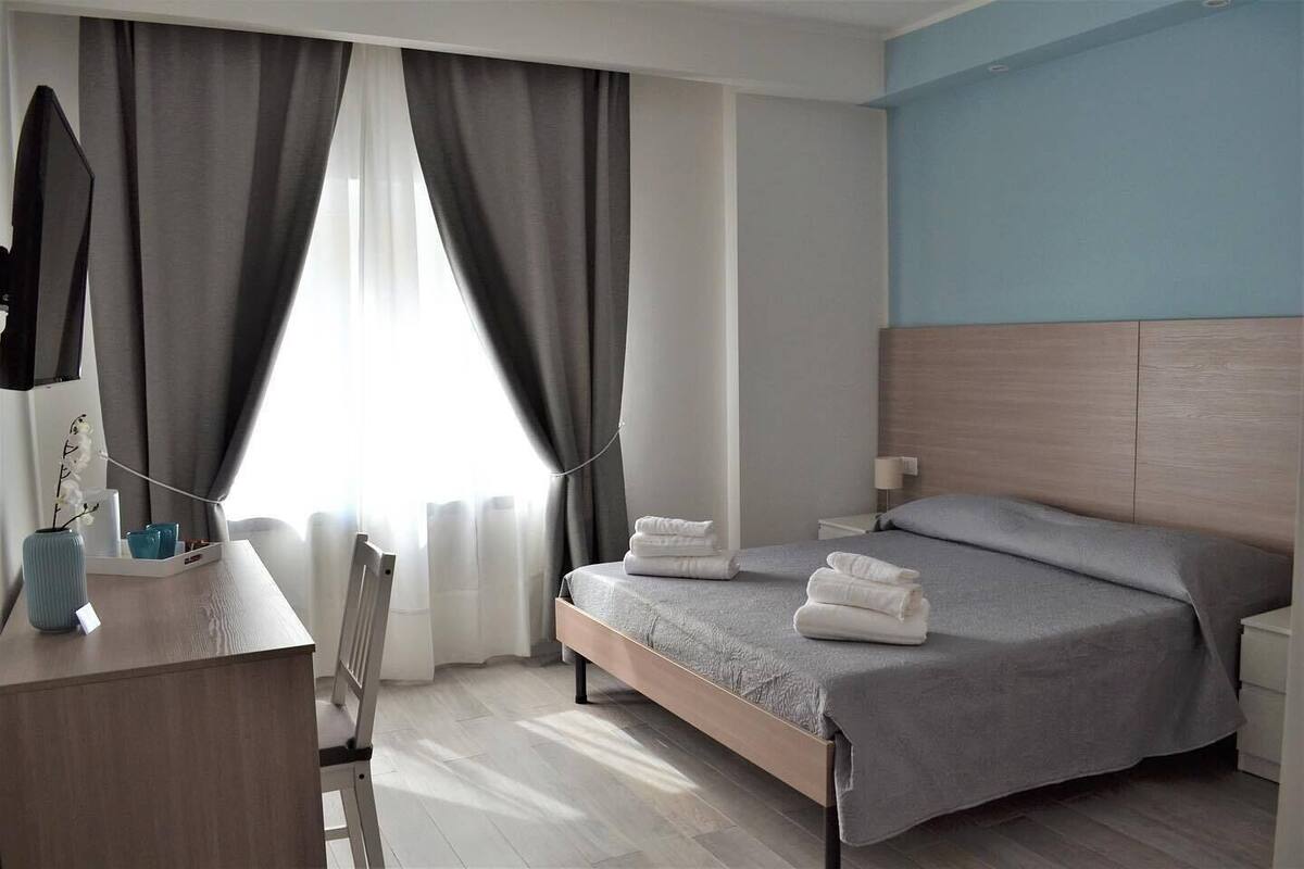 Ein Hotelzimmer mit Bett, Nachttisch und Schreibtisch mit Stuhl.