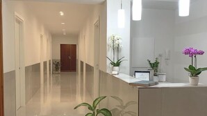 Un moderno vestíbulo de hotel con un largo pasillo, una recepción y plantas en macetas.