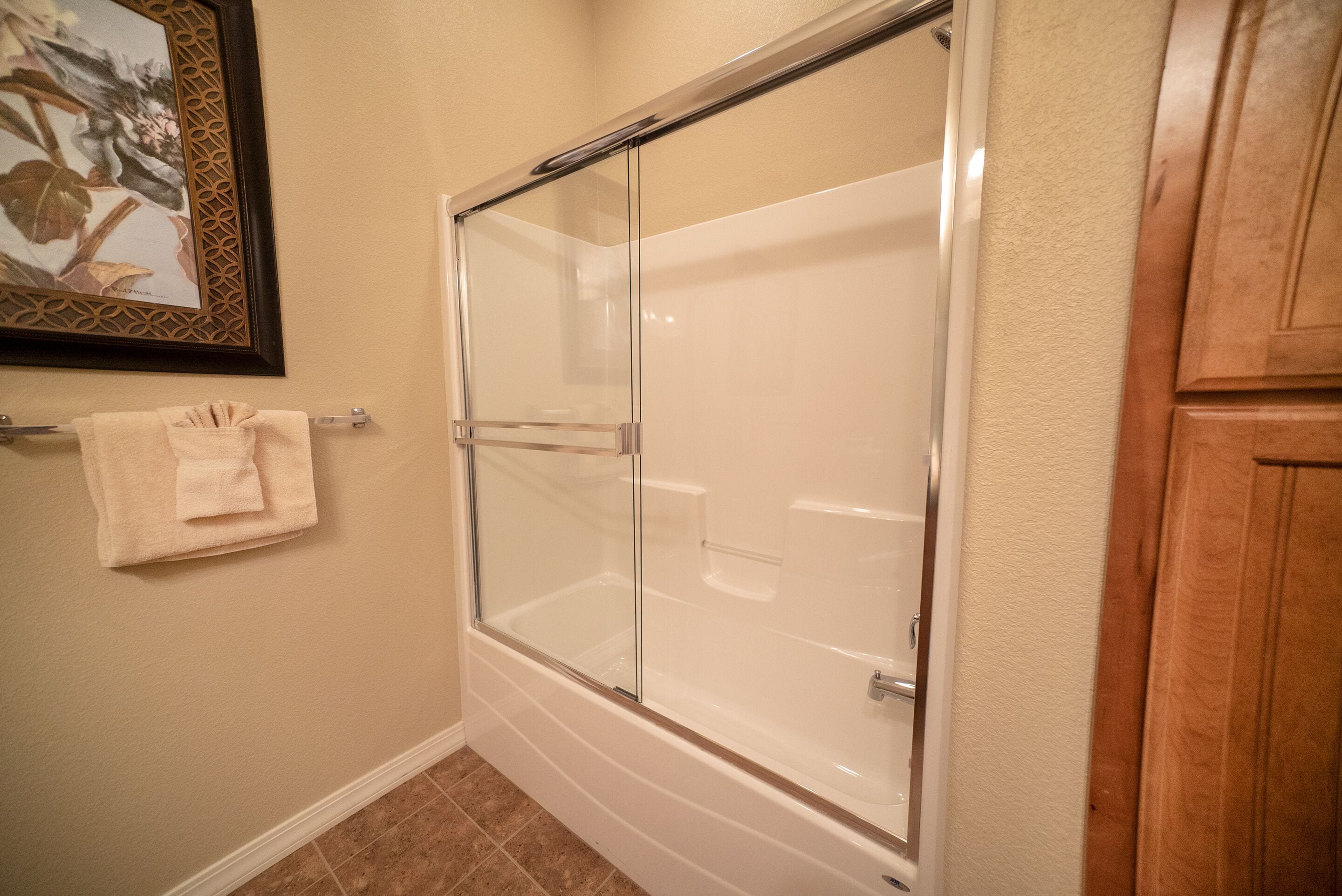 A bathroom with a glass-enclosed shower, a towel rack, and wooden cabinetry.