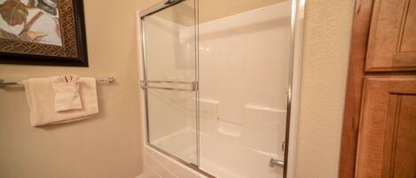 A bathroom with a glass-enclosed shower, a towel rack, and wooden cabinetry.