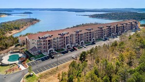 Ein mehrstöckiges Hotel mit Schwimmbad, Parkplatz und Blick auf einen See.