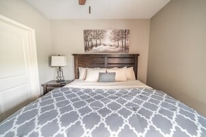 A bedroom with a bed, a nightstand, a lamp, and a painting on the wall.