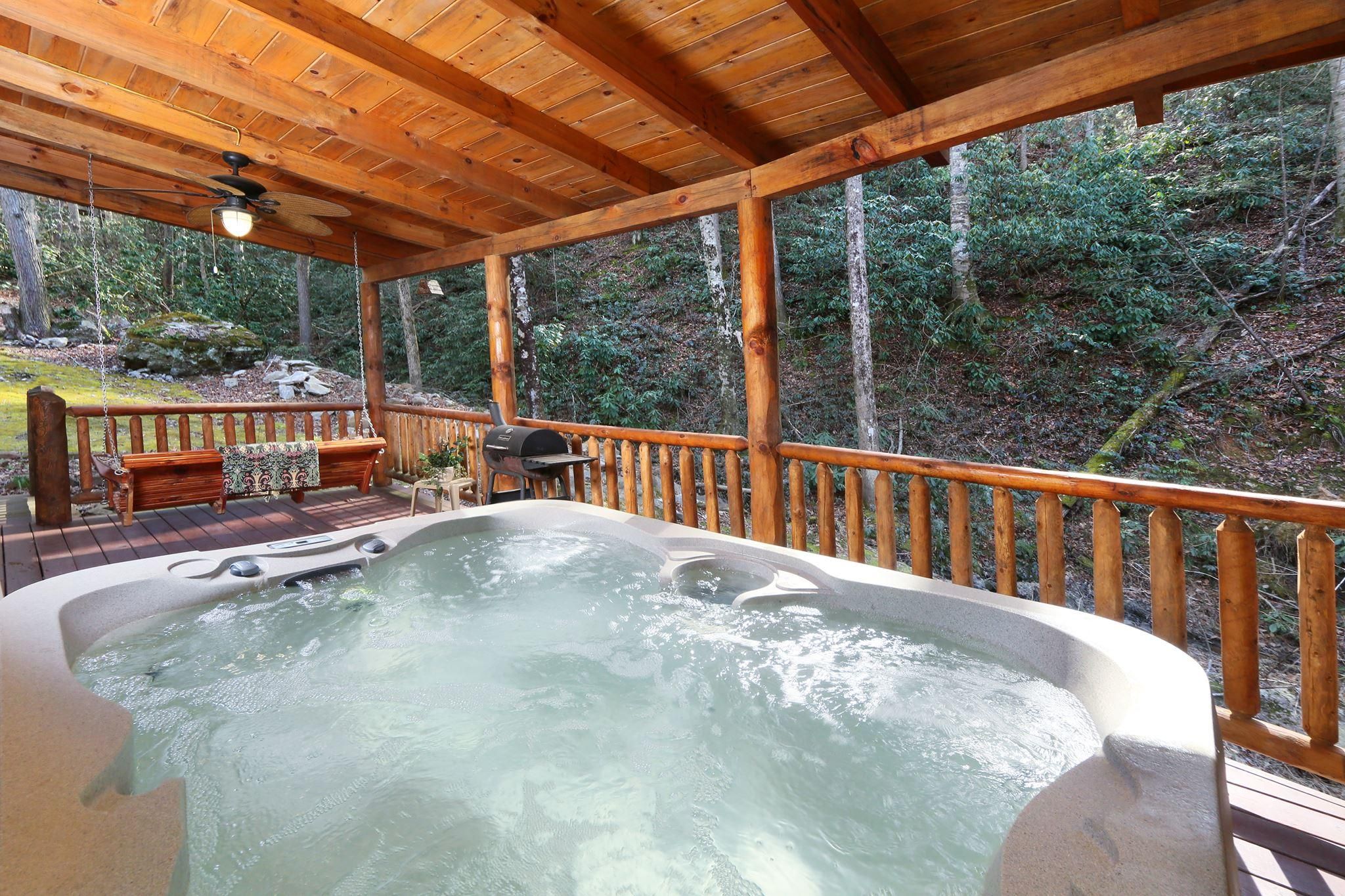 A hot tub in a wooden deck area with a wooden railing and a bench.