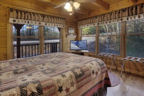 Ein gemütliches Schlafzimmer mit einem großen Bett, einem Fernseher und Blick ins Freie.