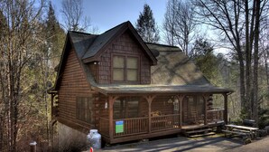 A log cabin with a porch, a satellite dish, and a sign advertising a bed and breakfast.