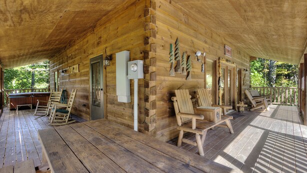 A wooden cabin with a covered porch, wooden furniture, and a small outdoor seating area. - A Beary Tale #258 (Sevierville)