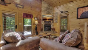 A cozy log cabin interior with a fireplace, wooden walls, and a comfortable seating area. - A Beary Tale #258 (Sevierville)