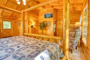 Ein Blockhaus-Zimmer mit einem Bett, einem Schreibtisch und einem Fenster.