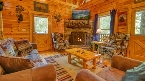 A cozy log cabin interior with a fireplace, wooden walls, and rustic decor.