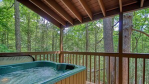 A hot tub on a wooden deck with a forest view.