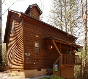 A wooden cabin with a balcony, a chimney, and a sign indicating it is a Mountain Hideaway.