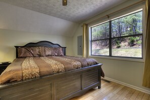 A bedroom with a large window, a wooden bed, and a white ceiling. - Bear Run Getaway #1136 (Gatlinburg)