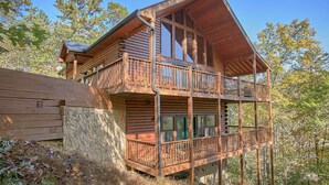 Eine zweistöckige Blockhütte mit Balkon und Steinunterbau.