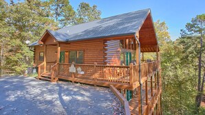 Eine Blockhütte mit Veranda und Terrasse, umgeben von Bäumen.
