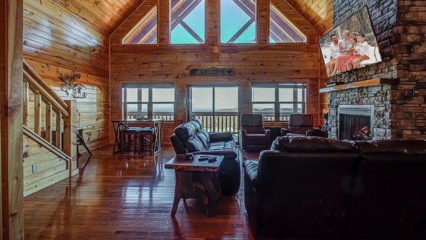 A log cabin interior with a wooden ceiling, a fireplace, a leather sofa, and a dining area. - Majestic View Lodge #426 (Sevierville)