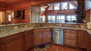 A kitchen with wooden cabinets, granite countertops, and a built-in dishwasher. - Majestic View Lodge #426 (Sevierville)